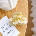 Creamy beige camellia flower hair claw clip with a glossy shell finish on a wooden table - 6cm / Yellow