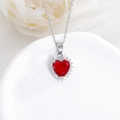 Dettaglio della collana con ciondolo a cuore rosso e diamanti su sfondo bianco puro - Rosso