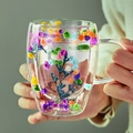 Hand holding a double-walled glass mug with colorful dried gypsophila flowers inside - Colorful Dried Flower Style (A-1125)