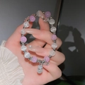 Detail eines Perlenarmbands mit lila Perlen, weißen Opalen und silbernem Blumenanhänger - Violetter Stern (25# Armband-Violetter Stern)