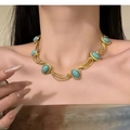 Primer plano de collar vintage dorado con piedras turquesas usado en el cuello - Collar de piedras preciosas azules