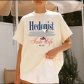 Μπεζ βαμβακερό oversized t-shirt με γραφικό τύπωμα Hedonist φορεμένο σε εξωτερικό χώρο - S / Βερικοκί