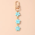 Dettaglio di ciondoli a fiore in smalto azzurro su un portachiavi dorato raffinato - Chiusura ad Anello / Blu