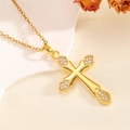 Detail einer goldenen Kreuzkette mit Zirkonia-Inlay auf strukturiertem Seidenhintergrund - Spitze Halskette / Gold