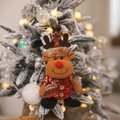 Christmas reindeer plush ornament with red plaid vest hanging on a flocked holiday tree - Elk