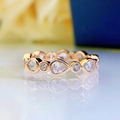 Macro shot of rose gold pear and round cut stones set in a wavy band with reflection - US 7 / Rose Gold