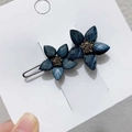 Detaillierte Makroansicht der blauen Blumen-Haarklammer mit Strasssteinen auf Goldbasis - Blau Blume Stil