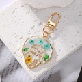 Detail of a gold face silhouette keychain with real blue and yellow dried flowers - White Yellow Flower