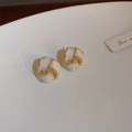 Macro shot of cream white geometric earrings with gold-plated spiral texture - White Geometric Spiral