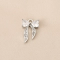Macro view of silver bow pendant with cubic zirconia inlay on textured fabric - Double Heart Zirconia Bow (PJ0242) / Silver