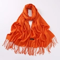Detailed macro view of the premium orange cashmere scarf featuring elegant fringe tassels - Orange Red