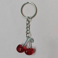 Detailed view of red resin cherry keychain with silver leaves on pink surface - Silver Chain Red Cherry (Silver Leaf)