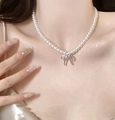 Vue détaillée d'un collier de perles avec pendentif nœud argenté sur la clavicule - Chaîne de Perles Pendentif Noeud Argenté / 4# Collier - Blanc