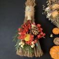 Close-up of decorative straw broom with dried flowers, pine cone and Triquetra charm - Broom+Flowers+Celtic Knot