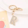 Close-up of golden metal letter R keychain with sparkling rhinestones and lobster clasp - Letter R