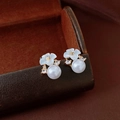 Dettaglio di orecchini a fiore bianco con perla su sfondo in pelle scura - Madreperla a Cinque Petali Bianca (3# Perno in Argento)