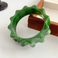Macro detail of wide green marble resin bangle with wavy gear edges and glossy finish - Green