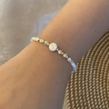Close-up of a pearl and gold beaded bracelet with an engraved letter N charm on a wrist - Letter N Style (N)