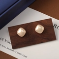 Detailed view of square freshwater pearl earrings on a dark wooden display stand - 12mm / 12mm Champagne