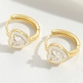 Detalle de los pendientes de corazón dorados con esmalte blanco y circonitas centrales - Blanco