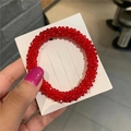 Detailed view of a red crystal beaded hair tie on a fashion jewelry display card - Red