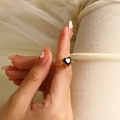 Macro shot of an elegant gold heart ring featuring a black gemstone on model's finger - Gold Black Zirconia