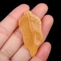 Hand carved yellow agate leaf pendant featuring detailed natural stone veins - Topaz