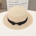 Close-up of beige straw sun hat with black ribbon bow on a clean white desk surface - One Size / Beige