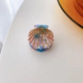 Detail of a small shell-shaped acetate hair clip with pink marble texture and gold lines - Lake Blue