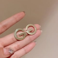 Close-up of golden metal G-shaped stud earrings with polished finish held in hand - Gold Letter G Ear Studs (24#)