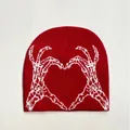 Close-up detail of red knitted beanie featuring a white heart-shaped skeleton hands jacquard - Red & White