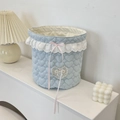 Close-up of light blue quilted fabric storage basket with lace trim and pink bow detail - Heart Light Blue