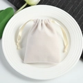 Close-up of a velvet drawstring jewelry pouch in cream white on a white porcelain dish - 5*7cm / Off White