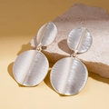 Macro view of geometric silver earrings with brushed metallic texture on stone - Brushed Double Disk Design / Silver