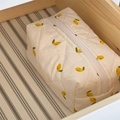 Quilted fabric cosmetic bag with lemon pattern and white zipper in a wooden drawer - White Lemon