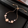 Detail of rose gold sliding bracelet with square cat-eye stones and zircon accents - Gold