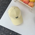 Macro shot of embroidered black CC letters on a light yellow cotton baseball cap - Beige