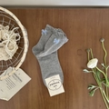 Gray cotton socks with light blue side bows and scalloped cuffs on a wooden background - One Size / Grey