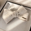 Dettaglio fiocco in misto lana con placchetta in metallo dorato fatta a mano - Beige