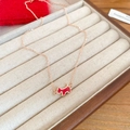 Détail du collier en or rose avec pendentif chien rouge sur plateau à bijoux en velours - Collier / Or rose Rouge