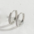 Dettaglio macro di orecchini a cerchio in argento con zirconi scintillanti incastonati - Argento con zircone bianco