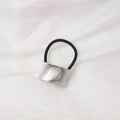 Close-up of a silver brushed metal hair ring with a black elastic band on white fabric - Curved Brushed (1) / Silver