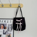 Détail du sac à main en satin noir avec nœuds en ruban rose suspendu à un crochet mural - Sac Uniquement / Noir