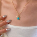 Close-up of a gold necklace featuring a turquoise stone and bird charm on a model's neck - Bird and Leaf Pendant Style (7834)