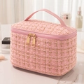 Pink tweed cosmetic bag with gold zippers and leather handle on marble surface - Pink