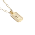 Gros plan d'un pendentif rectangulaire plaqué or avec texture tissée et cristaux - Lettre T