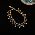 Close-up of golden multi-layer bracelet featuring lace mesh structure and cubic charms - Bracelet - Gold