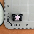 Macro shot of 1.6cm black resin bow with pink star detail on a metric measuring grid - Black Pink Bow Small