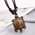 Close-up of brown resin turtle pendant with woven black rope and wooden beads decoration - Turtle / Brown