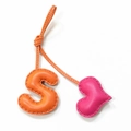 Nahaufnahme von handgefertigtem Taschenanhänger aus Leder mit S-Buchstabe und rosa Herzanhänger - Orange mit Rosenrotem Herz
